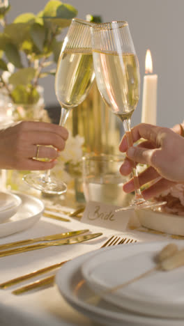 Vertical-Video-Close-Up-Of-Couple-Making-Toast-With-Champagne-At-Vertical-Video-Of-Table-Set-For-Meal-At-Wedding-Reception